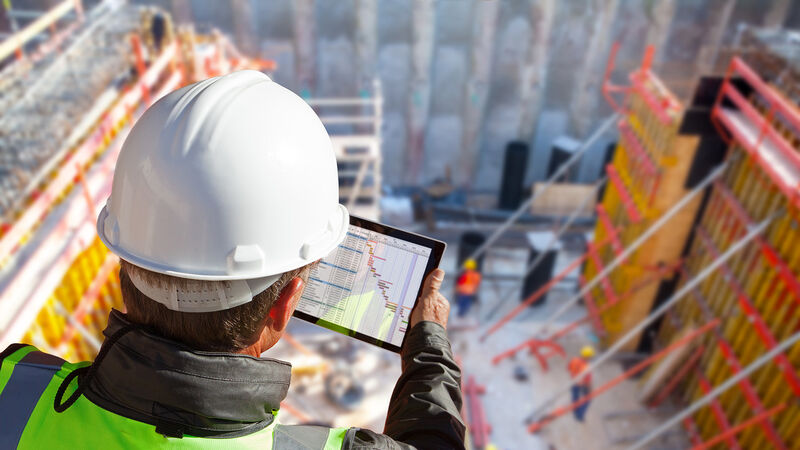 Construction engineer checking a project schedule on a tablet on site