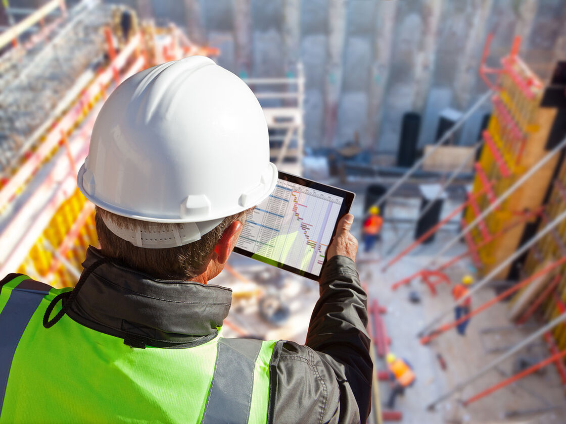 Construction engineer checking a project schedule on a tablet on site