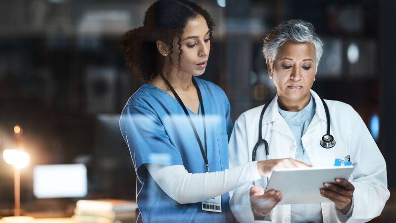 A doctor and nurse reviewing patient information on a tablet
